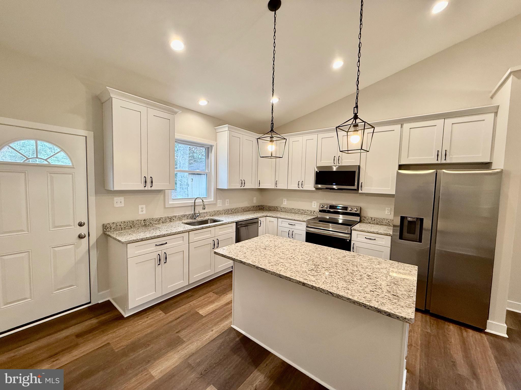 130 Poplar Lane Colonial Beach, VA 22443 - Photo 15 of 74 a kitchen with stainless steel appliances granite countertop a refrigerator a sink dishwasher a stove and white countertops with wooden floor