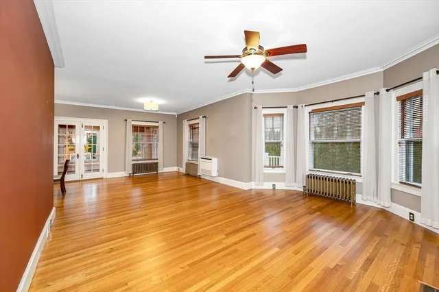 a view of empty room with wooden floor and fan