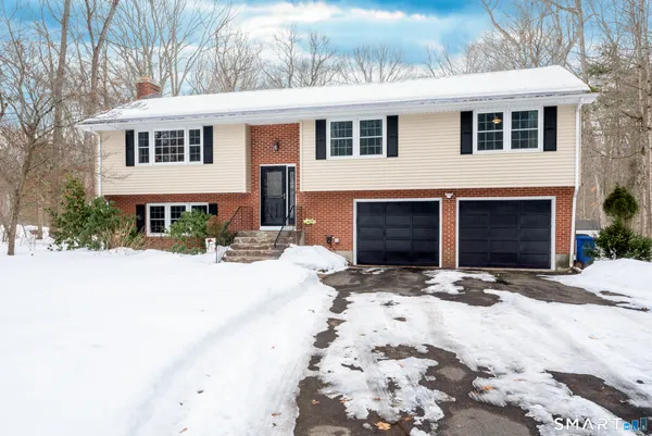 a front view of a house with a yard covered with snow