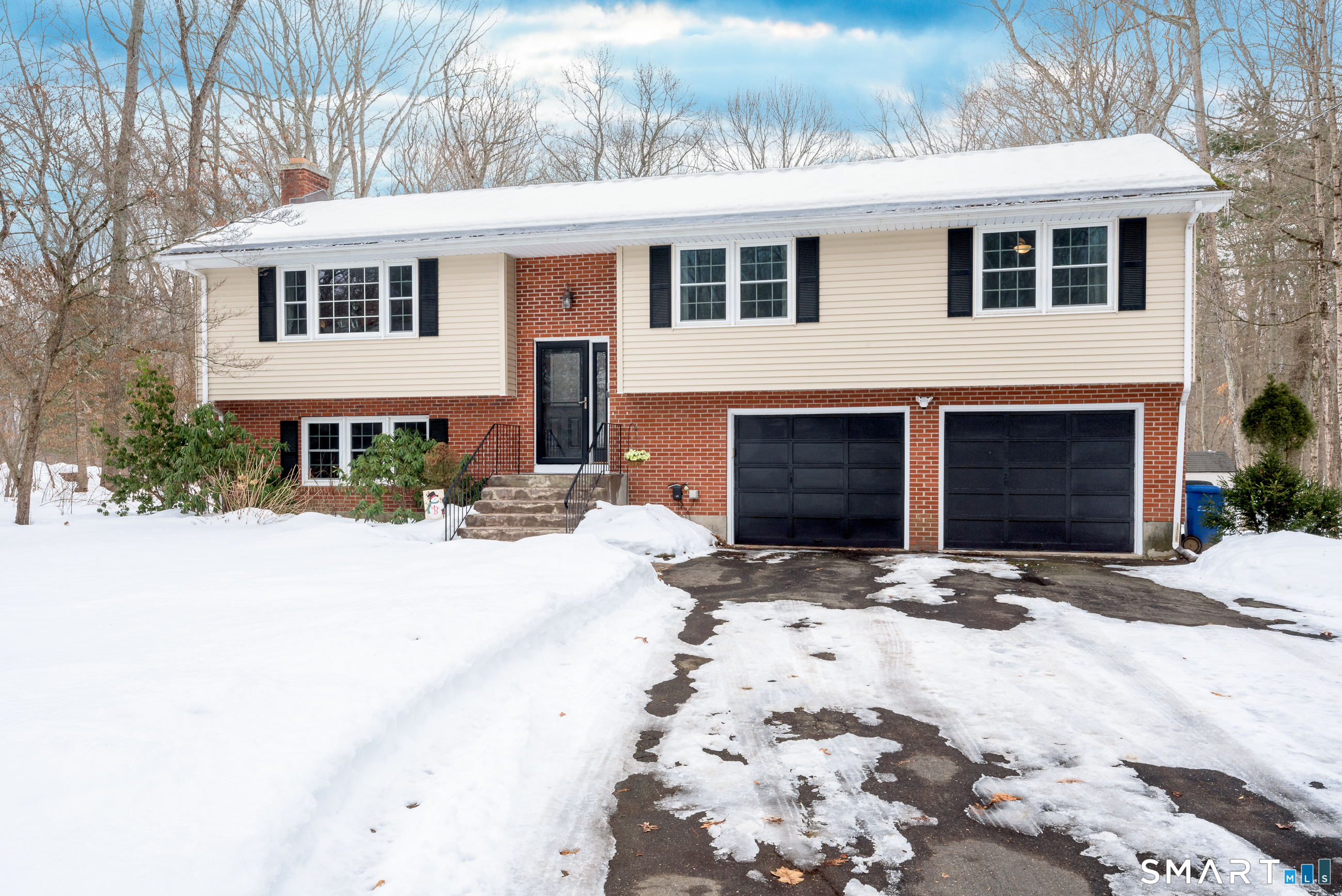 a front view of a house with a yard covered with snow
