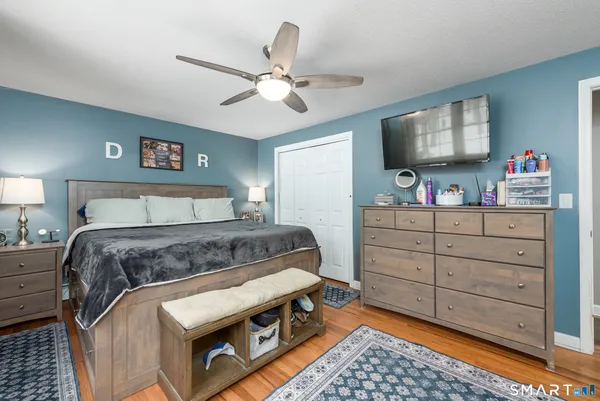 a bedroom with a bed and a flat tv screen on dresser
