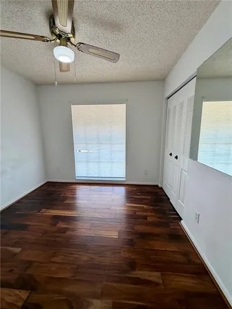 a view of an empty room with wooden floor fan and window