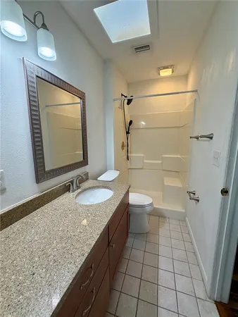 a bathroom with a granite countertop sink a toilet and shower