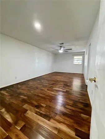 an empty room with wooden floor fan and windows