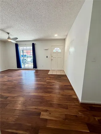 a view of an empty room with window and wooden floor