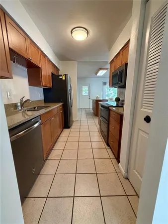 a kitchen with stainless steel appliances granite countertop a refrigerator a sink dishwasher and wooden cabinets