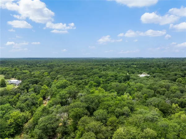 an aerial view of residential houses with outdoor space and trees