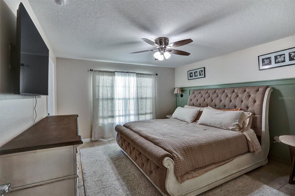5010 Treasure Cay Road Tavares, FL 32778 - Photo 11 of 32 a bedroom with a large bed and a flat tv screen on dresser