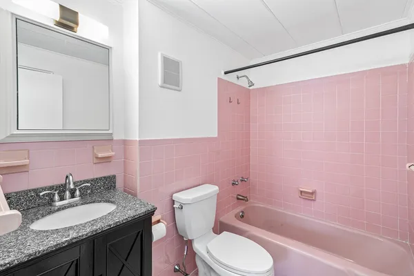 a bathroom with a granite countertop bathtub sink vanity mirror and toilet