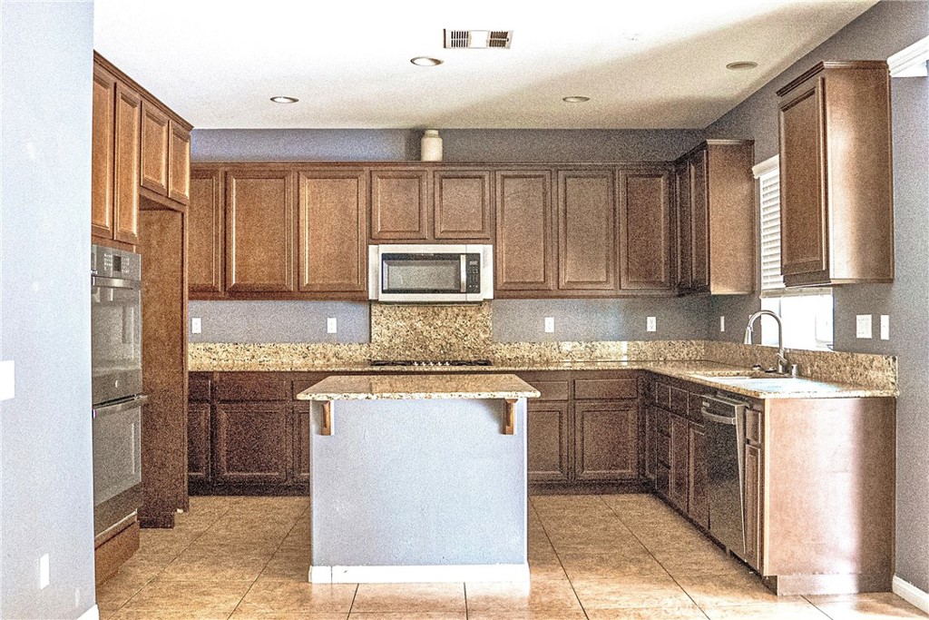 1373 Aztec Court Beaumont, CA 92223 - Photo 18 of 56 a kitchen with kitchen island granite countertop a sink stove and refrigerator
