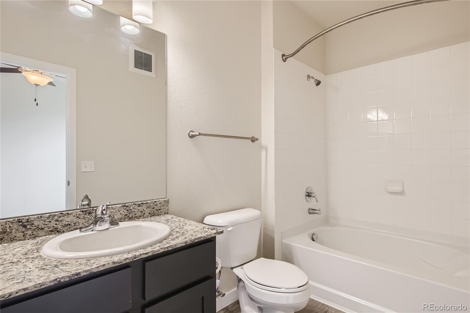 4100 Albion Street, Unit 514 Denver, CO 80216 - Photo 13 of 31 a bathroom with a granite countertop sink toilet mirror and shower