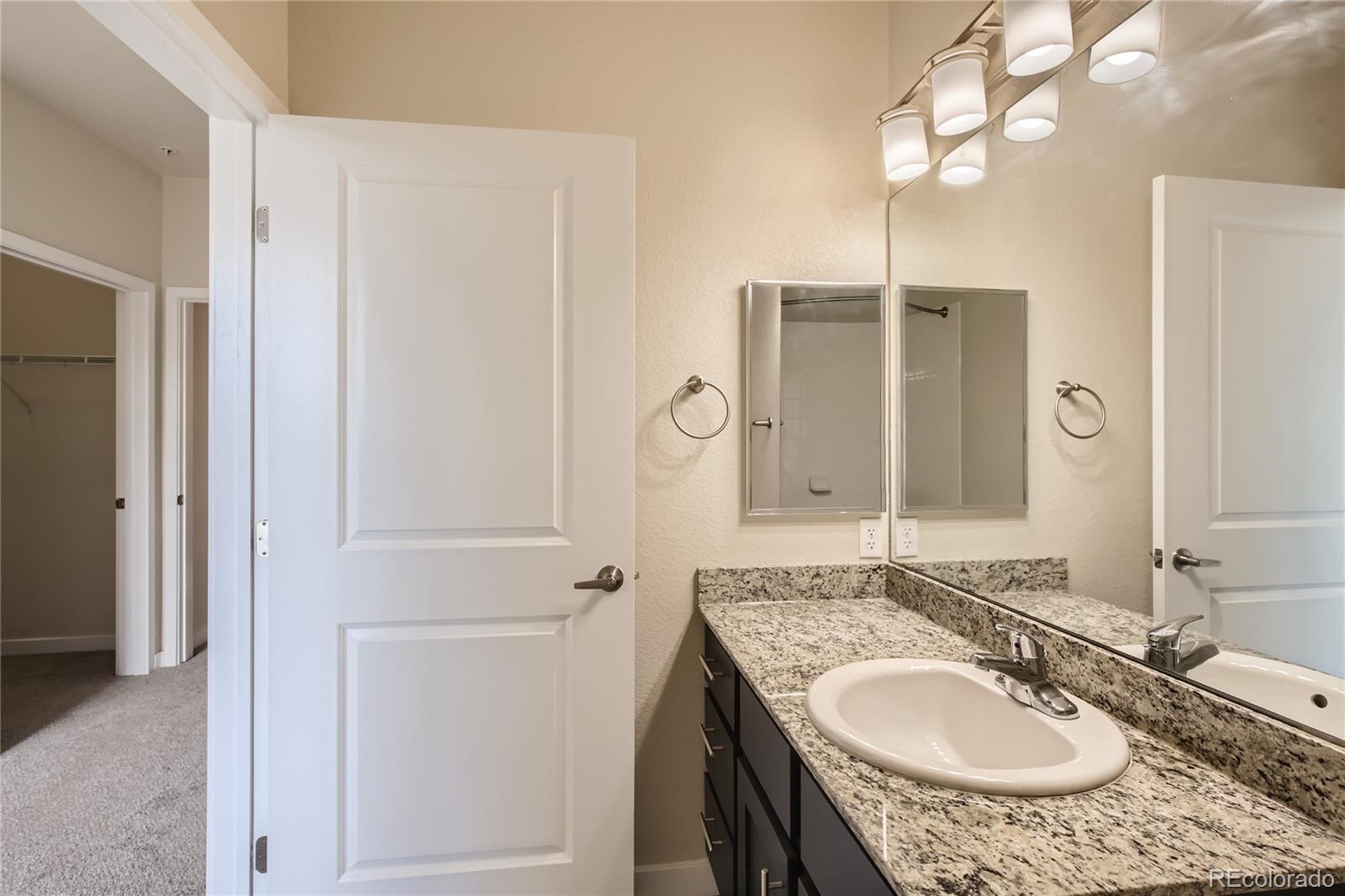 4100 Albion Street, Unit 514 Denver, CO 80216 - Photo 14 of 31 a bathroom with a granite countertop sink a mirror and shower