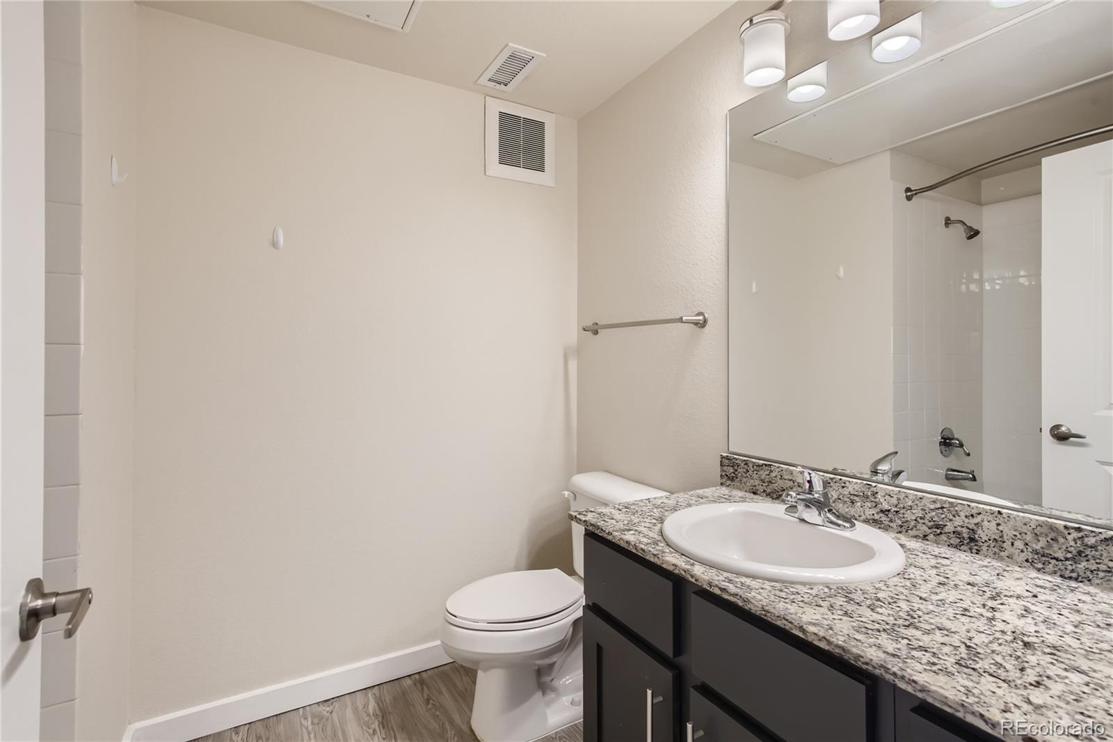 4100 Albion Street, Unit 514 Denver, CO 80216 - Photo 19 of 31 a bathroom with a granite countertop sink and a toilet