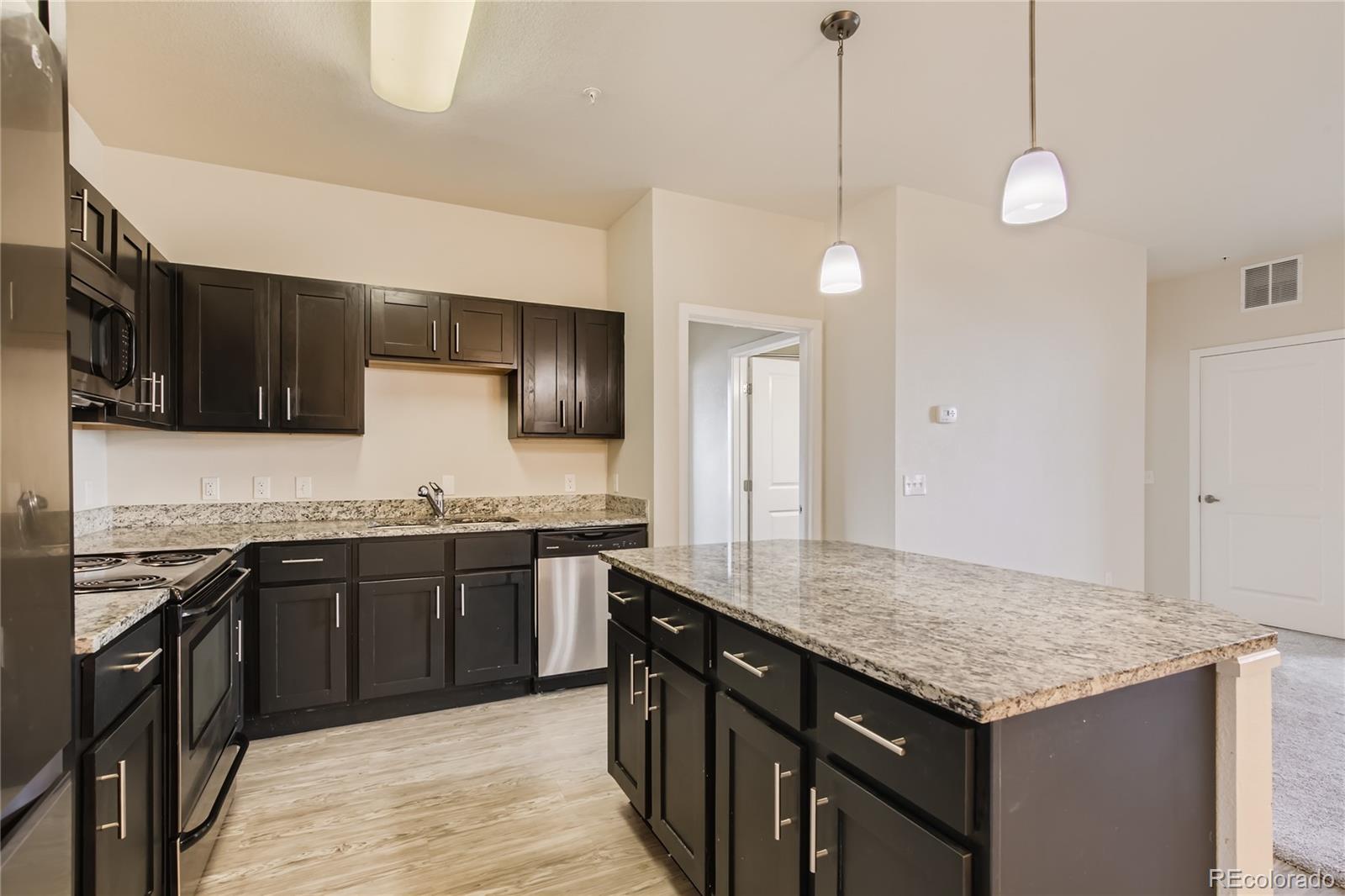4100 Albion Street, Unit 514 Denver, CO 80216 - Photo 7 of 31 a kitchen with stainless steel appliances granite countertop microwave stove top oven and cabinets