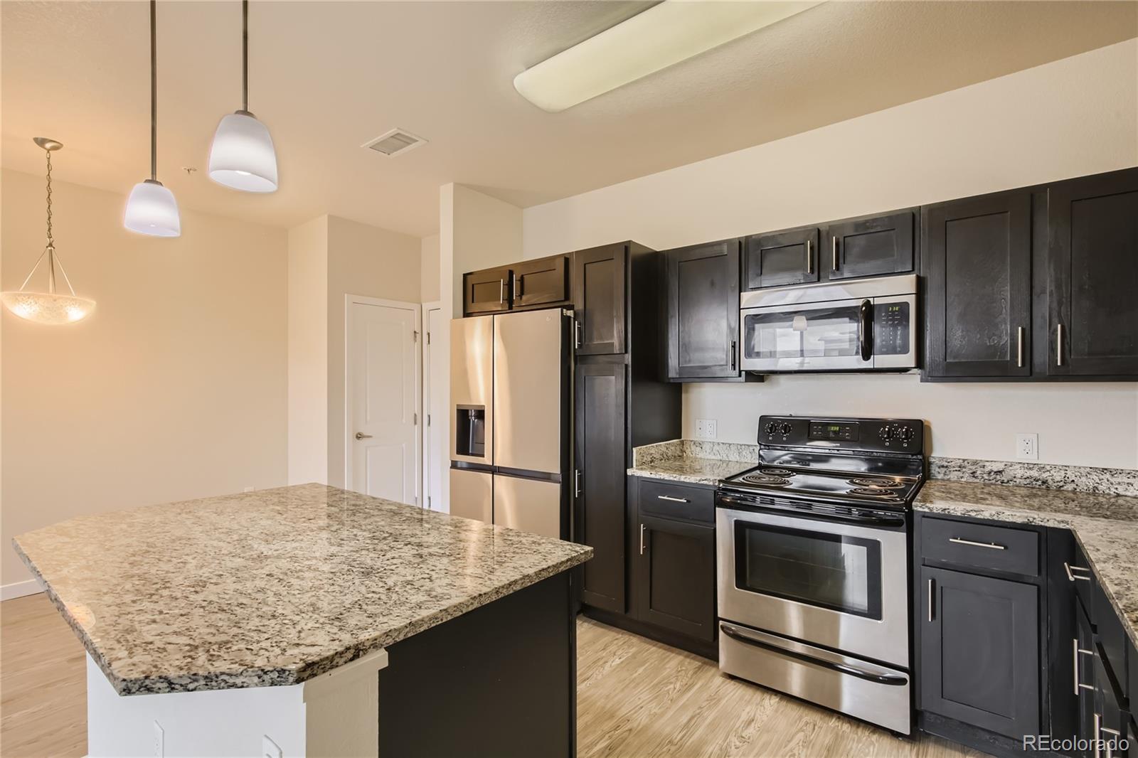 4100 Albion Street, Unit 514 Denver, CO 80216 - Photo 8 of 31 a kitchen with stainless steel appliances granite countertop a stove a refrigerator and a sink