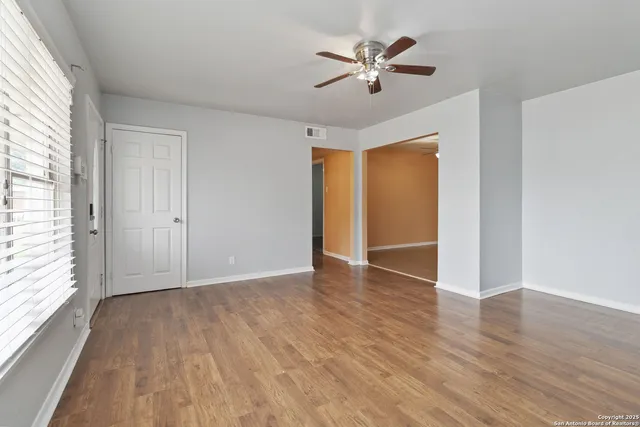 an empty room with wooden floor and windows