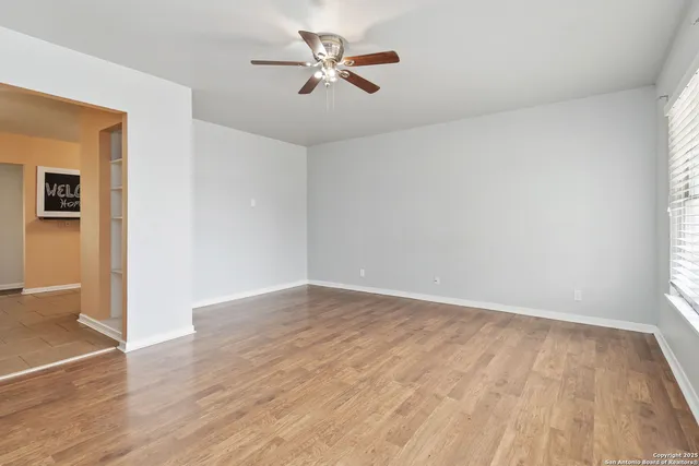 an empty room with wooden floor and a ceiling fan