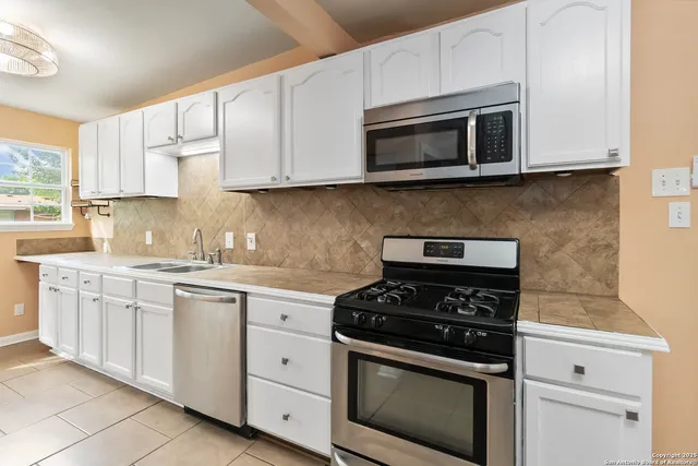 a kitchen with stainless steel appliances granite countertop grey cabinets a stove a sink and dishwasher