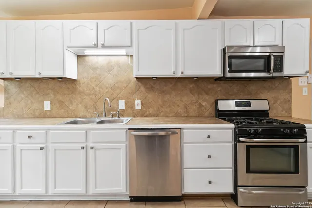 a kitchen with white cabinets and stainless steel appliances