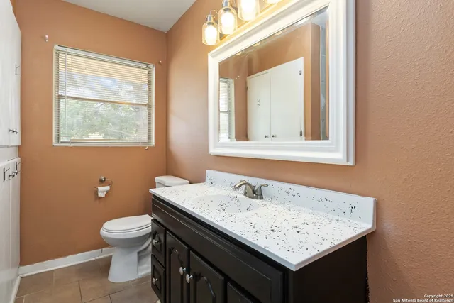 a bathroom with a granite countertop sink a toilet and a window