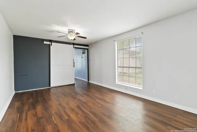 a view of an empty room with wooden floor and a window