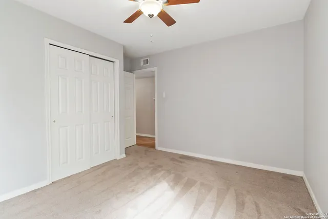 an empty room with a ceiling fan and carpet