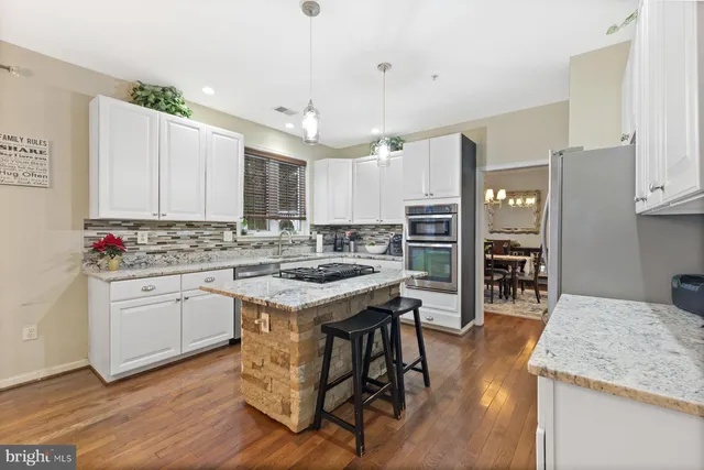 a kitchen with stainless steel appliances kitchen island granite countertop a stove refrigerator and cabinets