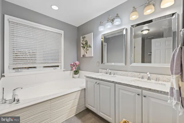 a bathroom with a sink double vanity granite tub and a mirror