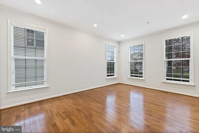 a view of an empty room with wooden floor and windows
