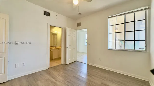 an empty room with wooden floor cabinet and windows