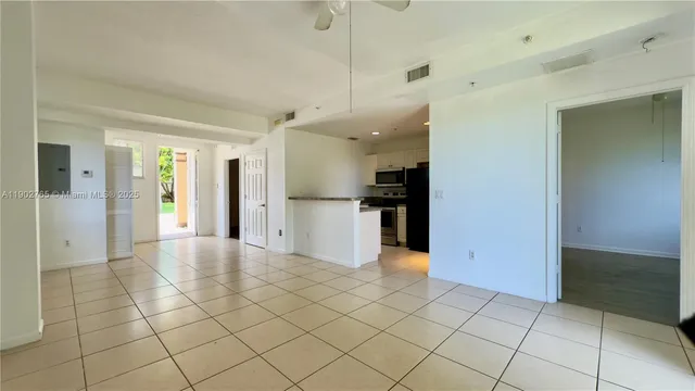 a view of a kitchen with refrigerator and an empty room
