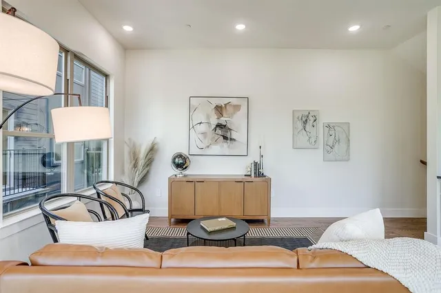 a living room with furniture a rug potted plant and a large window