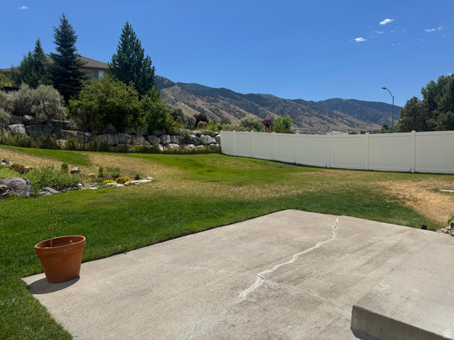 88 Canterbury Lane Logan, UT 84321 - Photo 33 of 37 Expansive backyard featuring a concrete patio, a private white vinyl fence, and a tiered rock retaining wall