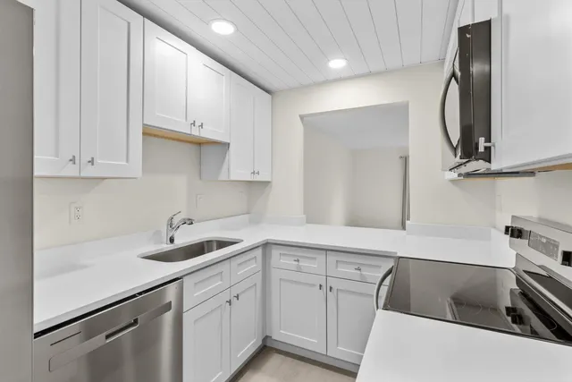 a kitchen with white cabinets stainless steel appliances and sink
