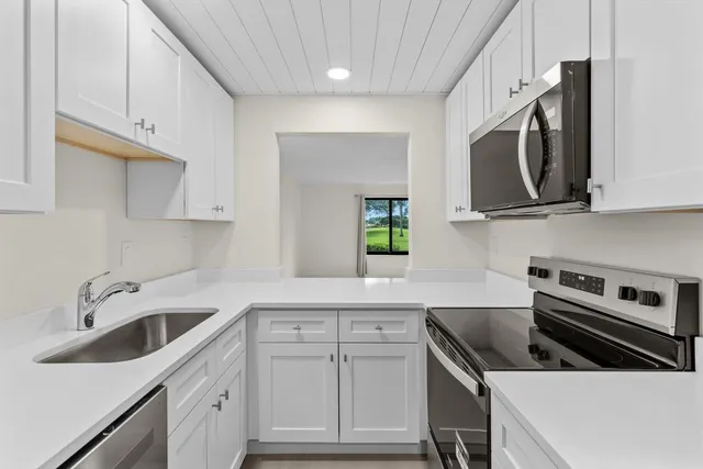 a kitchen with stainless steel appliances a stove a sink a microwave and cabinets