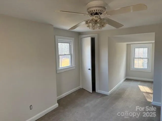 an empty room with a chandelier fan and windows