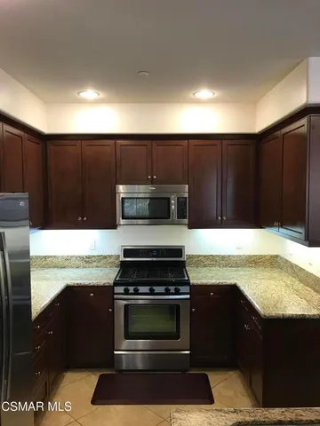 a kitchen with kitchen island granite countertop stainless steel appliances wooden cabinets and a sink