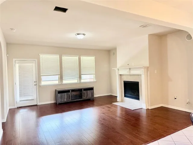 an empty room with wooden floor a fireplace and windows