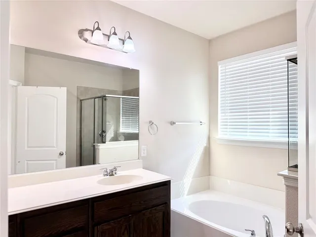 a bathroom with a tub a sink and a window