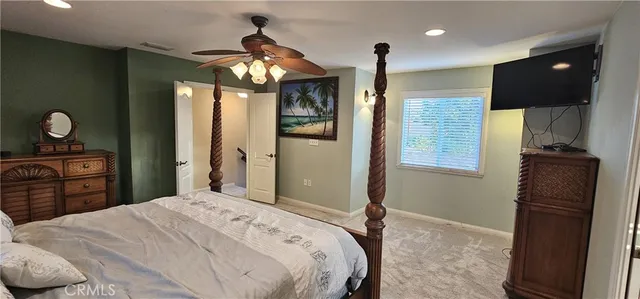 a bedroom with a bed and a flat tv screen on dresser