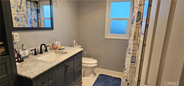 a bathroom with a granite countertop sink a toilet and a shower