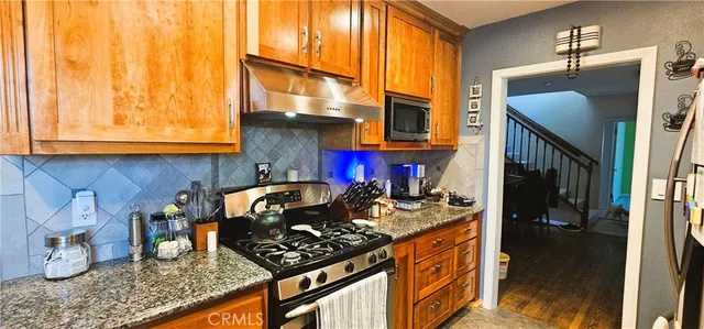 a kitchen with stainless steel appliances granite countertop a stove a sink and a microwave