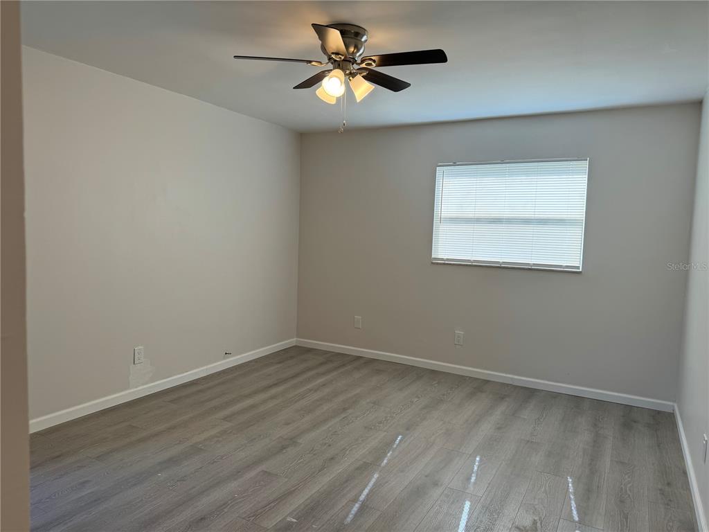 5521 Bay Boulevard, Unit 105 Port Richey, FL 34668 - Photo 2 of 15 a view of a room with wooden floor and a ceiling fan