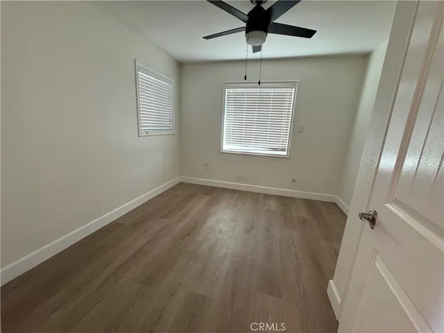 an empty room with wooden floor fan and windows