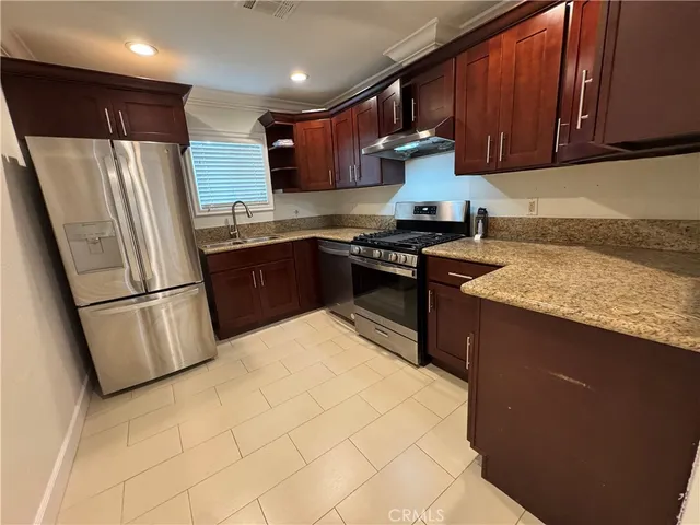 a kitchen with stainless steel appliances granite countertop a refrigerator a stove a sink and a microwave