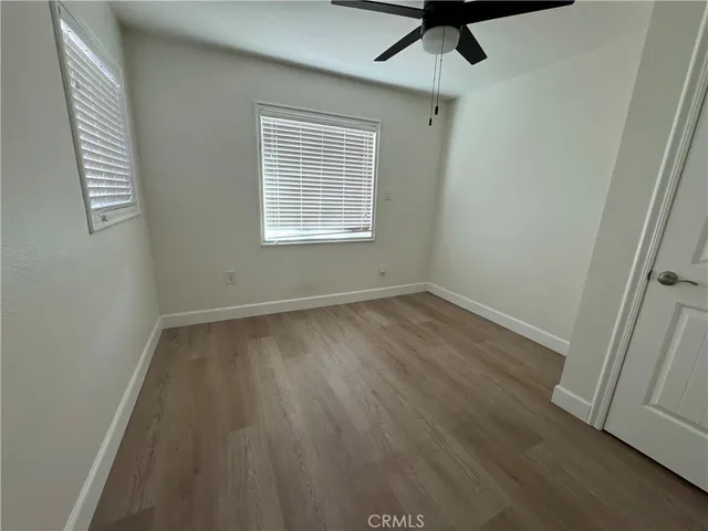 an empty room with wooden floor fan and windows
