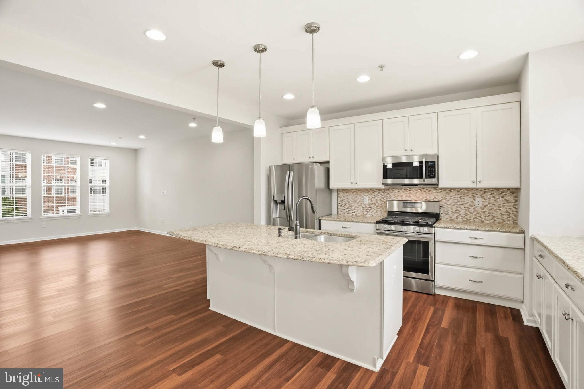 9817 Solar Course Laurel, MD 20723 - Photo 3 of 59 a kitchen with stainless steel appliances kitchen island granite countertop a stove a sink and white cabinets with wooden floor