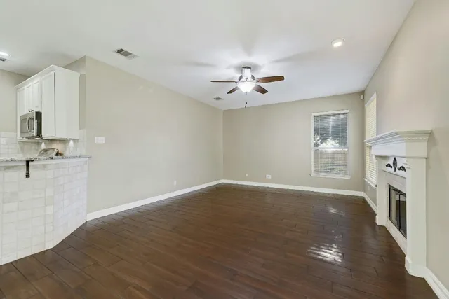 a view of an empty room with a kitchen and wooden floor