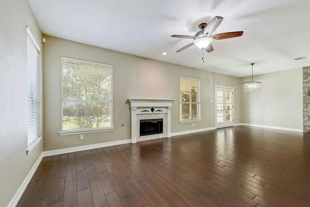 an empty room with wooden floor fireplace and windows