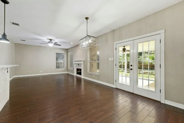 a view of an empty room with window and wooden floor